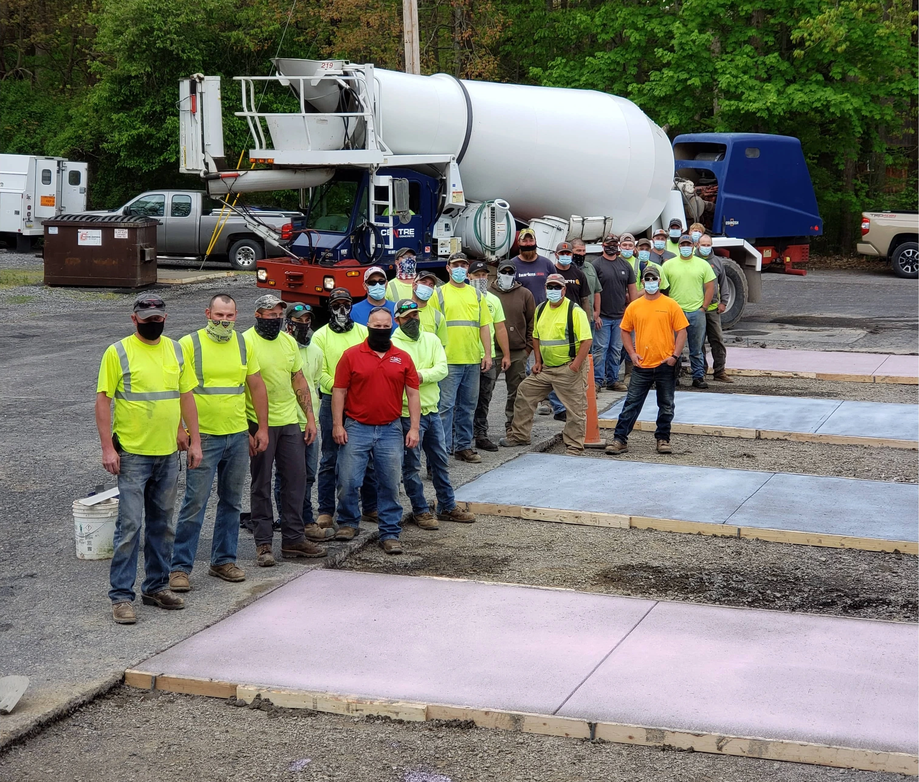 A group of Certified Concrete Finishers Course attendees stand in a group next to set concrete and in front of a concrete truck.